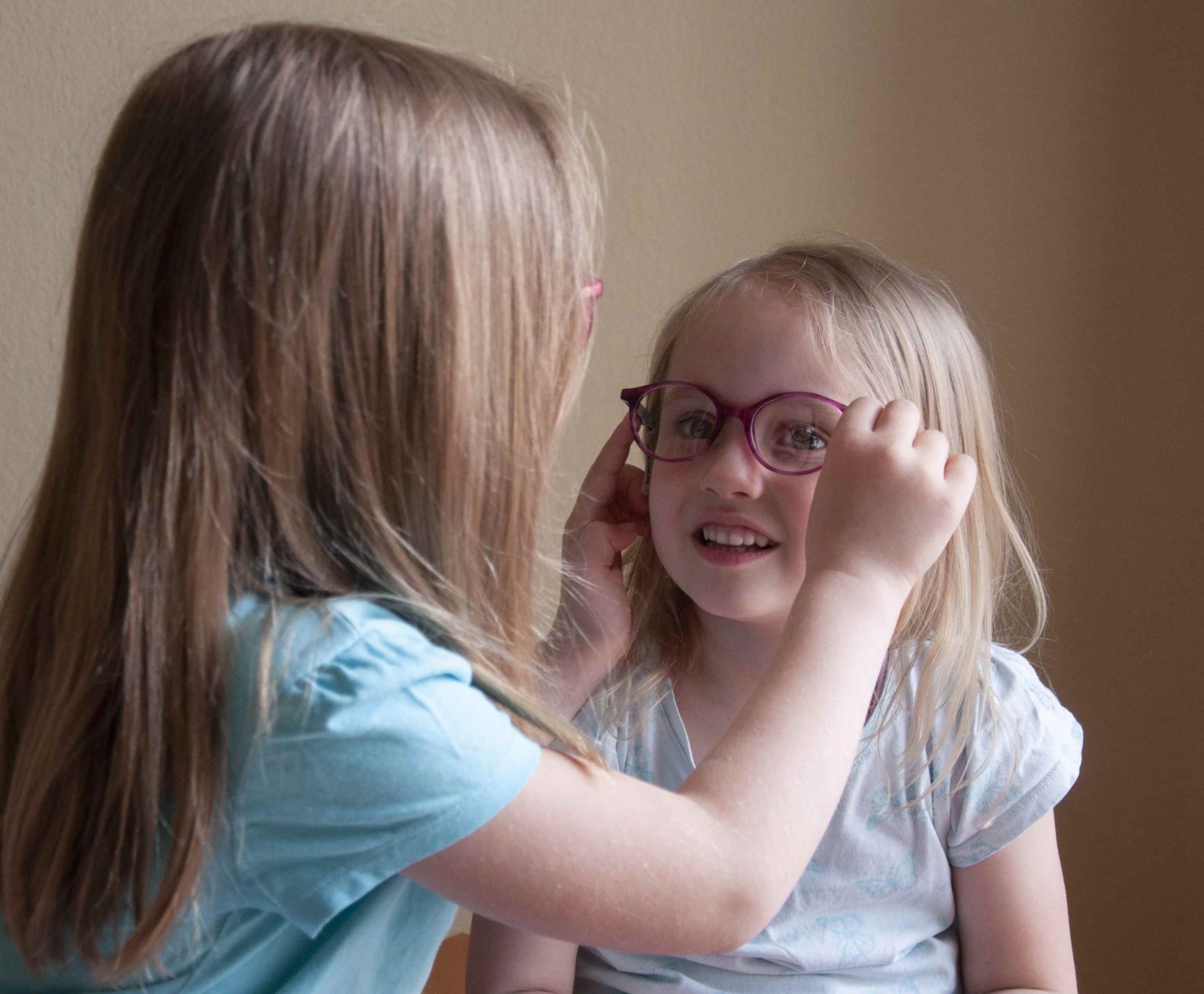 Kind setzt einem anderen Kind eine Brille auf