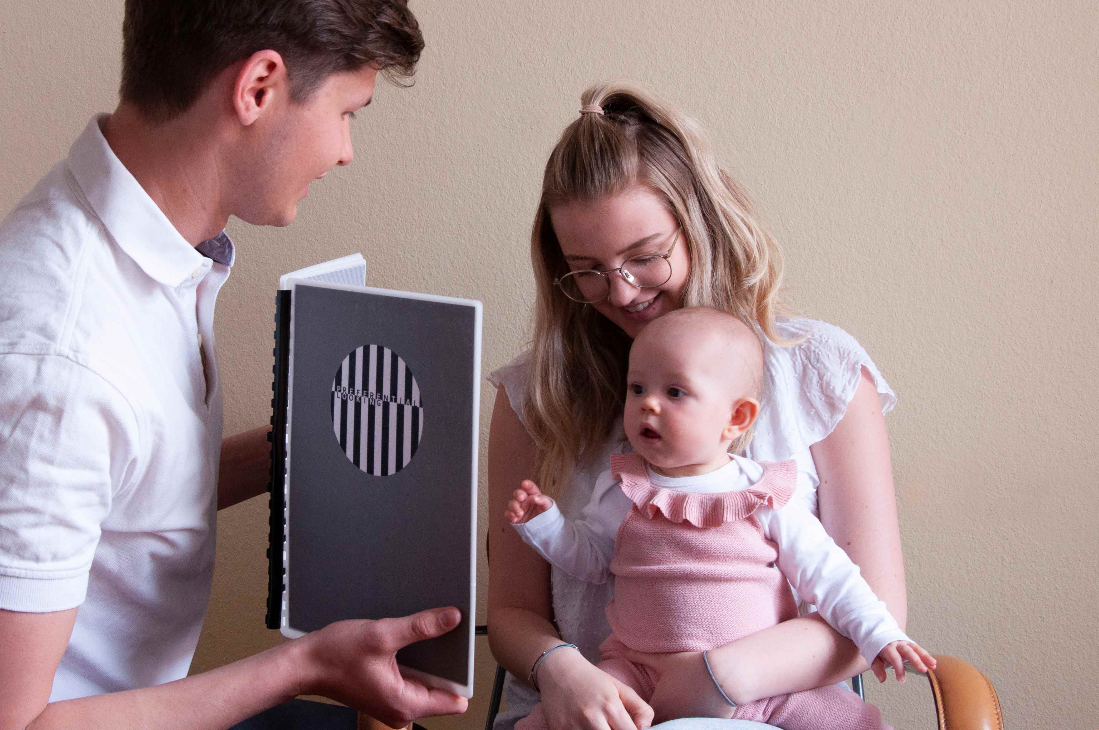 Kind bei der orthoptischen Untersuchung sitzend am Schoß der Mutter